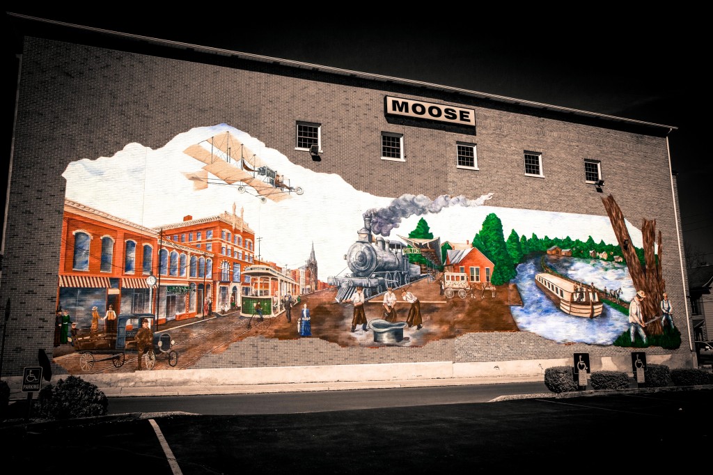 This particular mural focuses on the transportation history of Milton. Depicted are the town’s many means of transportation, from trucking, to the small dirt airport that used to exist, to the grand canal system. Also pictured are numerous inventions that have originated in Milton, including “fly nets” for horses and tub cars which enabled trains to haul liquid. Milton remains a prominent transportation hub in Pennsylvania today, so this story remains relevant.